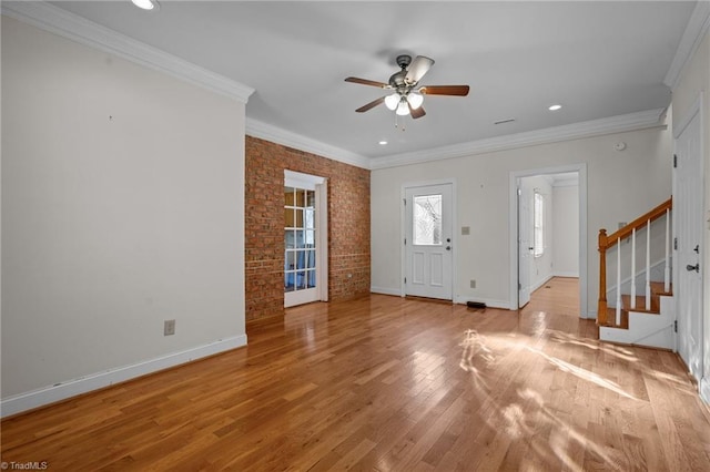 foyer entrance featuring ceiling fan, ornamental molding, brick wall, and light hardwood / wood-style floors