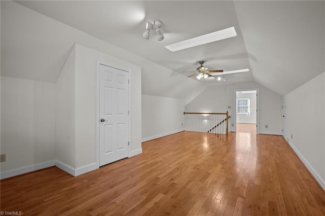 additional living space featuring wood-type flooring, lofted ceiling with skylight, and ceiling fan