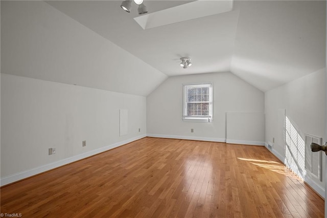 bonus room with light hardwood / wood-style flooring and vaulted ceiling with skylight