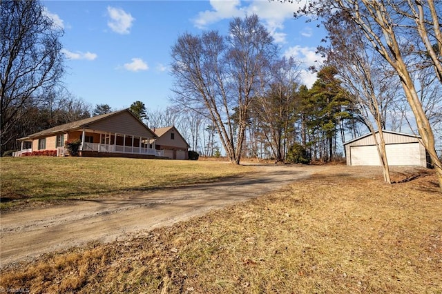 view of side of home featuring a garage, a yard, an outdoor structure, and covered porch