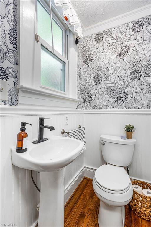 2065 Craig St, Winston-Salem, NC 27103 - half bathroom with wood finished floors, a wainscoted wall, a decorative wall, and crown molding