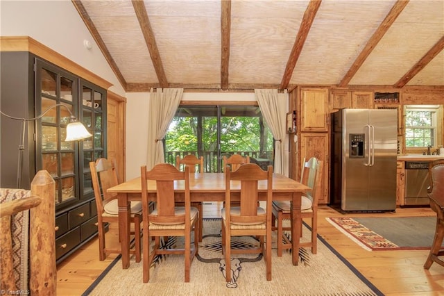 dining room featuring light hardwood / wood-style floors, sink, and lofted ceiling with beams