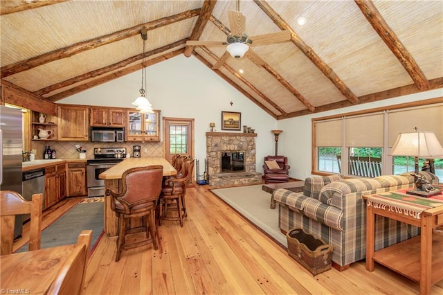 living room featuring a fireplace, a wealth of natural light, beam ceiling, and light wood-type flooring