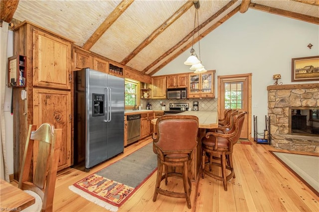 kitchen with light wood-type flooring, stainless steel appliances, kitchen peninsula, and a healthy amount of sunlight