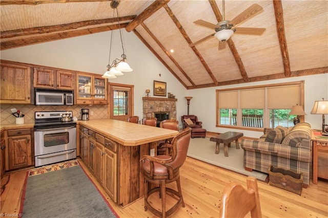 kitchen featuring a wealth of natural light, beam ceiling, appliances with stainless steel finishes, and light hardwood / wood-style flooring