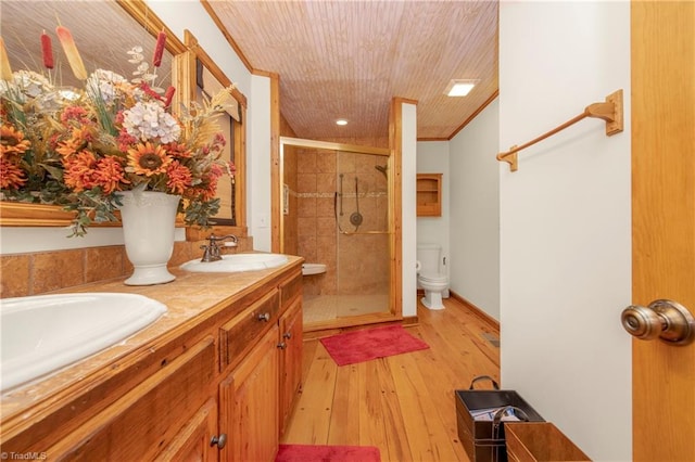 bathroom featuring hardwood / wood-style floors, vanity, crown molding, a shower with shower door, and toilet