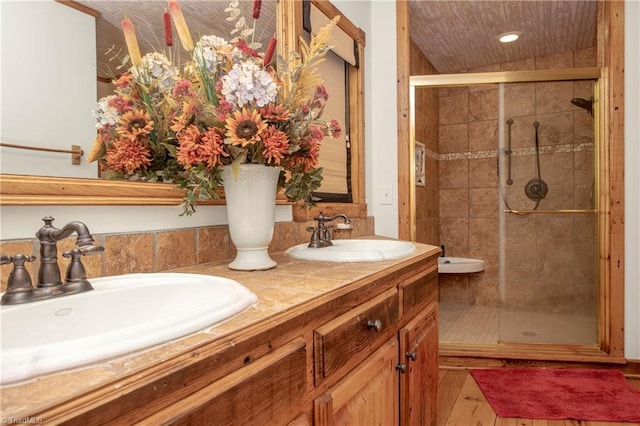 bathroom with hardwood / wood-style floors, vanity, and a shower with shower door