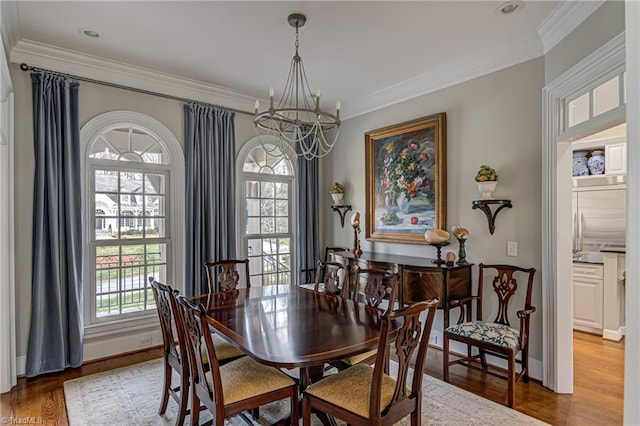 dining room with plenty of natural light, light hardwood / wood-style floors, crown molding, and a chandelier