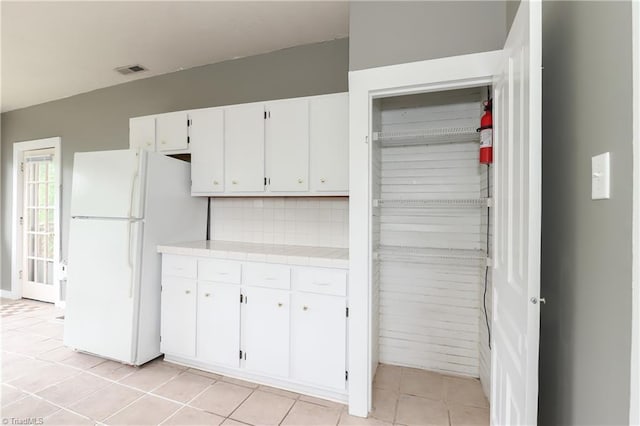 1025 W End Blvd, Winston-Salem, NC 27101 - kitchen featuring decorative backsplash, light tile patterned floors, white cabinetry, tile countertops, and freestanding refrigerator