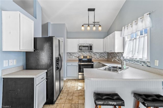 kitchen with lofted ceiling, a peninsula, a sink, appliances with stainless steel finishes, and backsplash