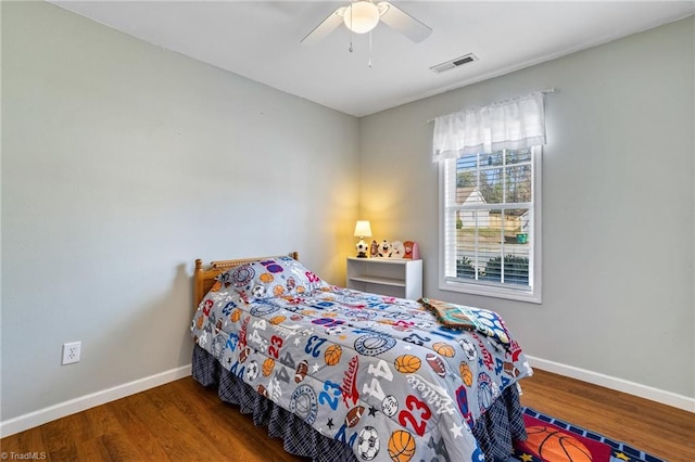 bedroom featuring a ceiling fan, wood finished floors, visible vents, and baseboards