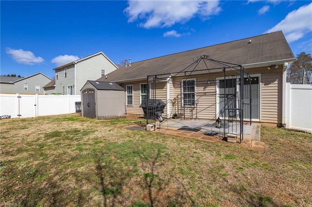 back of house with a storage unit, a lawn, a patio, a fenced backyard, and an outdoor structure