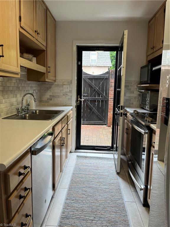 kitchen featuring sink, decorative backsplash, light tile patterned flooring, and stainless steel appliances