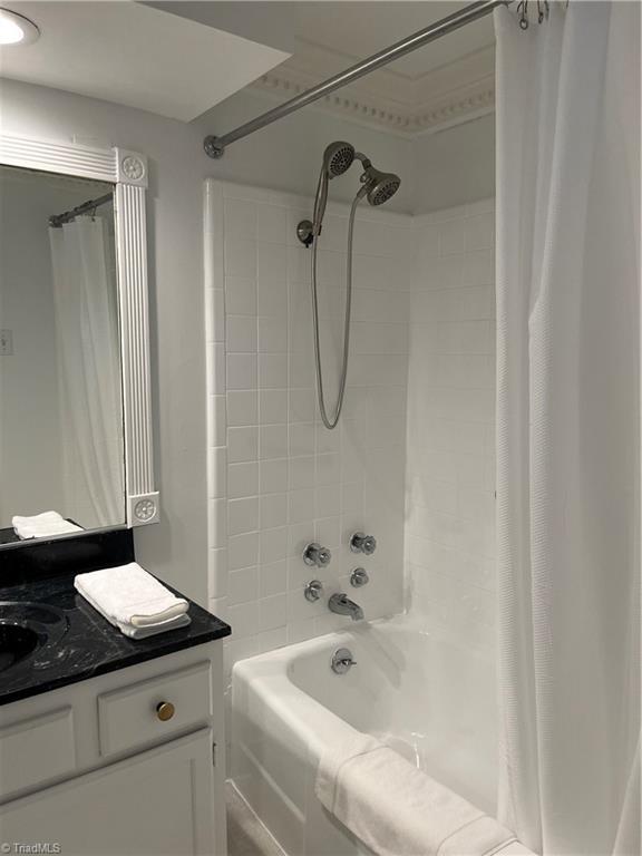 bathroom featuring shower / bathtub combination with curtain and vanity