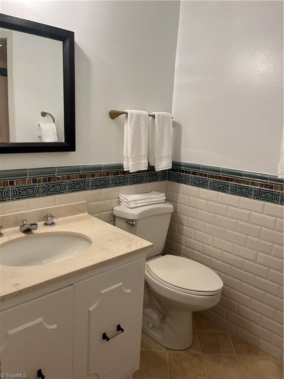 bathroom featuring tile patterned flooring, tile walls, toilet, and vanity