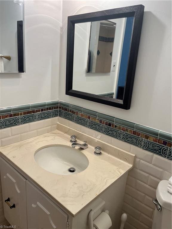 bathroom featuring toilet, vanity, and tasteful backsplash