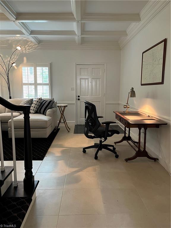 interior space featuring tile patterned floors, ornamental molding, beam ceiling, and coffered ceiling