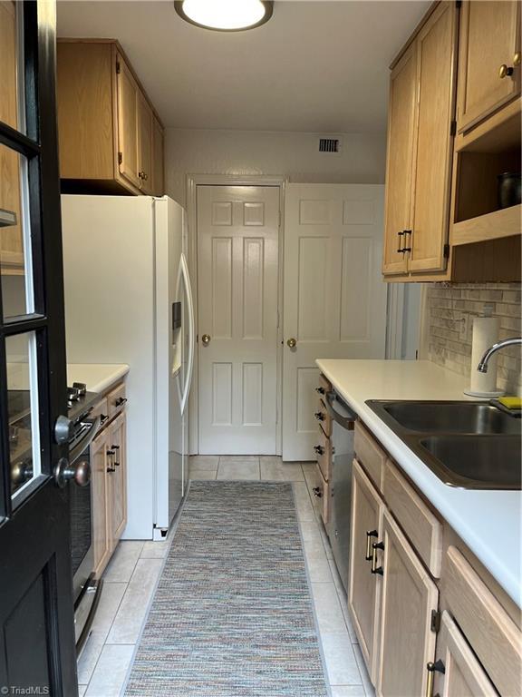 kitchen featuring sink, tasteful backsplash, stainless steel dishwasher, and light tile patterned floors