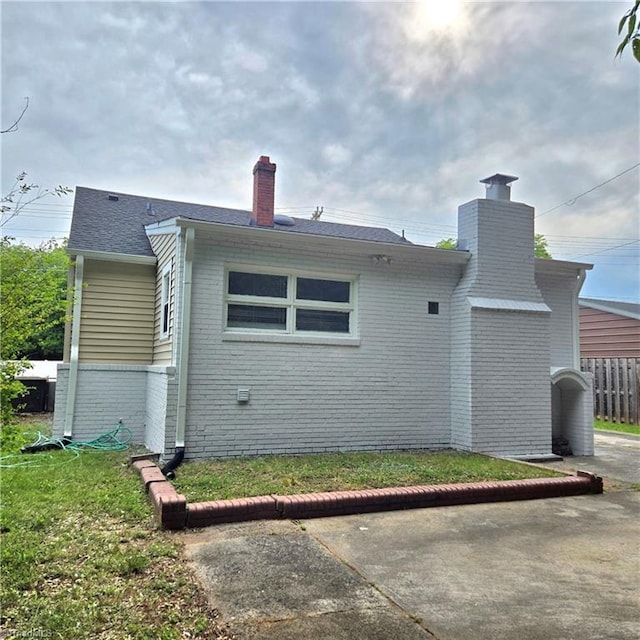 112 Kime St, Burlington, NC 27215 - view of side of property featuring a chimney, brick siding, and roof with shingles