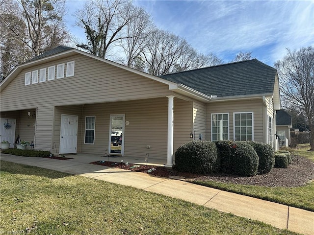 view of front of house with a shingled roof and a front yard