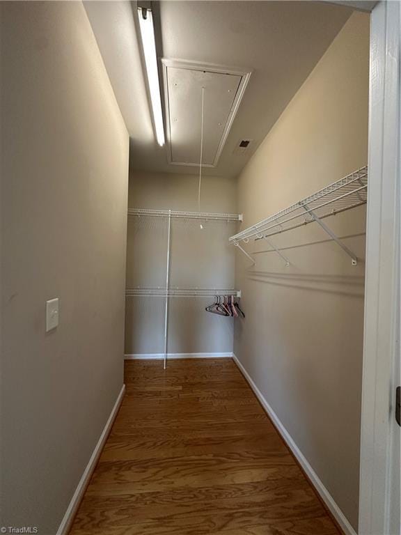 walk in closet with wood finished floors and attic access