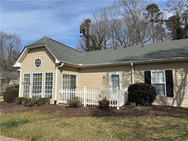 view of front of home with roof with shingles and a front yard