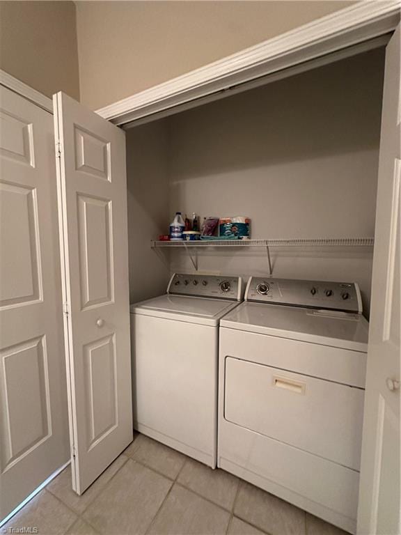 laundry room with laundry area, light tile patterned flooring, and washing machine and clothes dryer