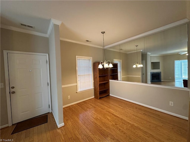 interior space with light wood-style floors, a chandelier, visible vents, and crown molding