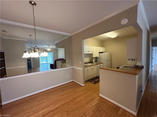 kitchen with white appliances, decorative backsplash, ornamental molding, light wood-type flooring, and a sink