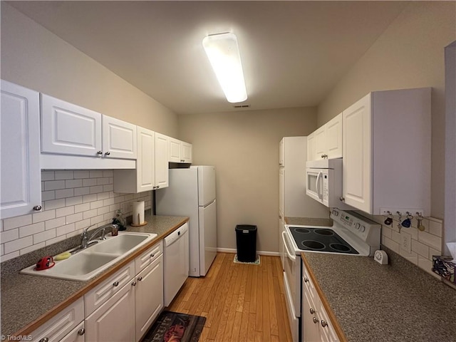 kitchen with white appliances, decorative backsplash, white cabinets, and a sink