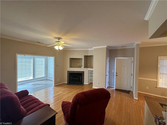 living area with light wood-style flooring, baseboards, ornamental molding, and a fireplace with flush hearth