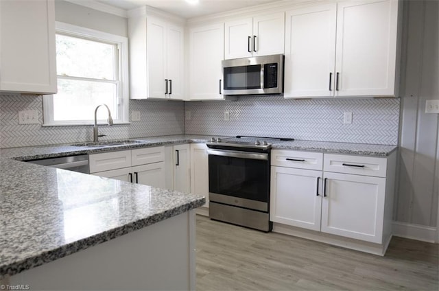 kitchen featuring light stone countertops, appliances with stainless steel finishes, tasteful backsplash, white cabinets, and sink