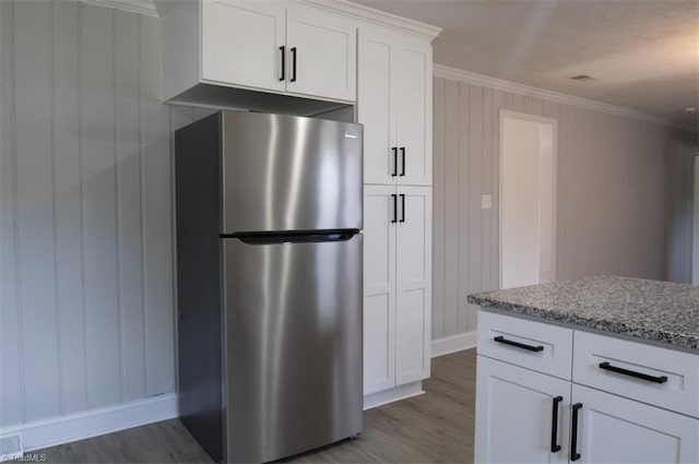 kitchen featuring light stone countertops, white cabinets, ornamental molding, dark hardwood / wood-style floors, and stainless steel fridge