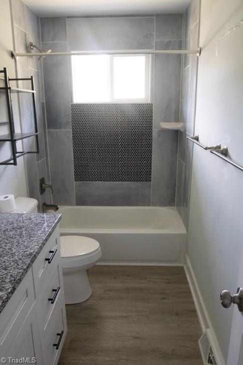 full bathroom with vanity, toilet, wood-type flooring, and tiled shower / bath combo