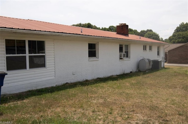 view of side of property featuring cooling unit, central AC unit, and a yard