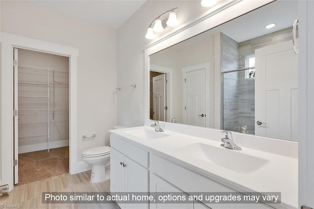 full bath with a tile shower, a spacious closet, toilet, double vanity, and baseboards