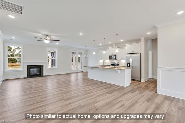 kitchen with stainless steel appliances, a breakfast bar area, a sink, white cabinets, and light wood-type flooring