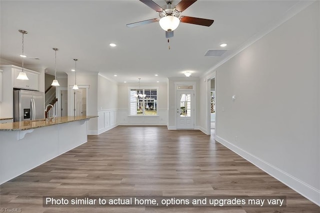 unfurnished living room featuring crown molding, a ceiling fan, recessed lighting, wood finished floors, and a sink