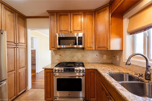 kitchen featuring stainless steel appliances, decorative backsplash, sink, light stone counters, and light tile patterned floors