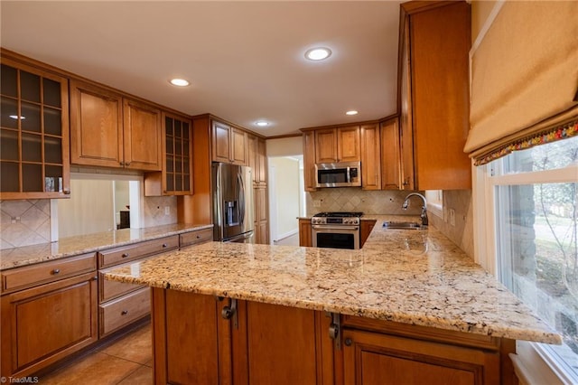 kitchen featuring kitchen peninsula, appliances with stainless steel finishes, sink, and light stone counters