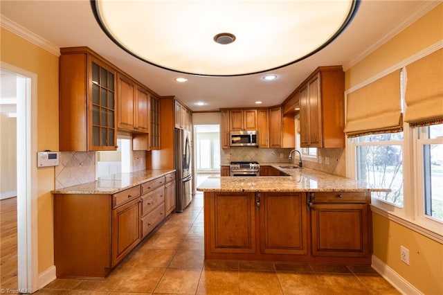 kitchen with stainless steel appliances, tasteful backsplash, plenty of natural light, kitchen peninsula, and light stone counters