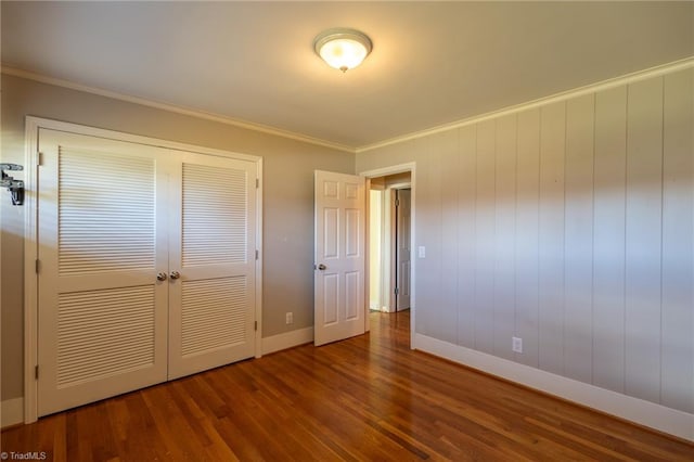 unfurnished bedroom featuring a closet, crown molding, and hardwood / wood-style flooring