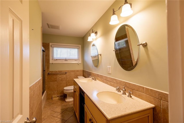 bathroom with toilet, tile walls, and vanity