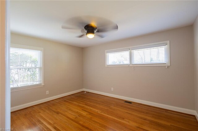 empty room featuring ceiling fan, light wood-type flooring, and a wealth of natural light