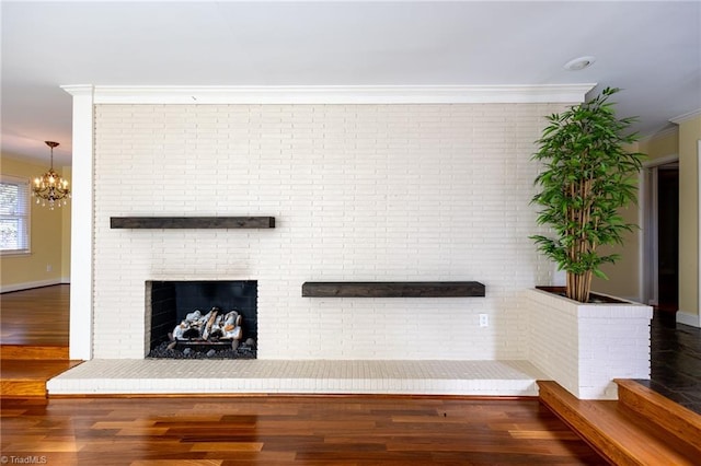 interior space featuring an inviting chandelier, a fireplace, crown molding, and hardwood / wood-style flooring