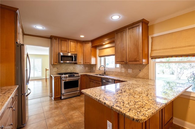 kitchen featuring kitchen peninsula, sink, light stone counters, and stainless steel appliances