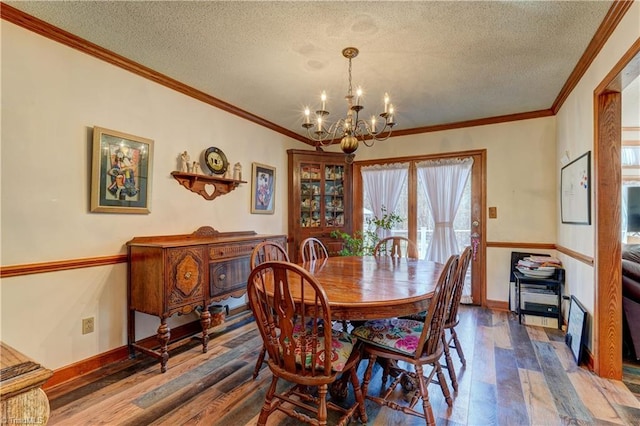 dining area featuring a textured ceiling, a notable chandelier, ornamental molding, and dark wood-type flooring