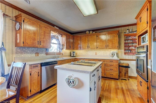 kitchen with sink, light hardwood / wood-style flooring, a textured ceiling, appliances with stainless steel finishes, and a kitchen island