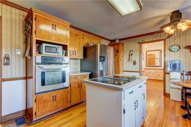 kitchen with white cabinetry, a center island, a textured ceiling, appliances with stainless steel finishes, and light wood-type flooring