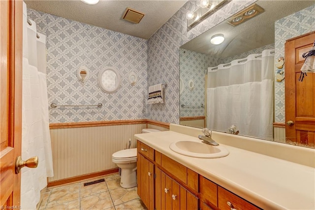 bathroom with vanity, tile patterned floors, a textured ceiling, and toilet